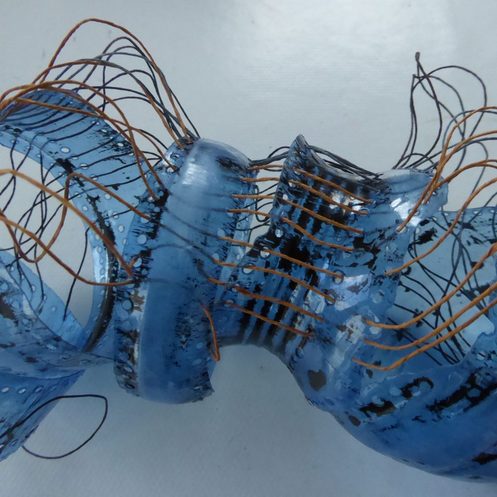 Fragments from blue plastic bottle laced together to form a writhing form