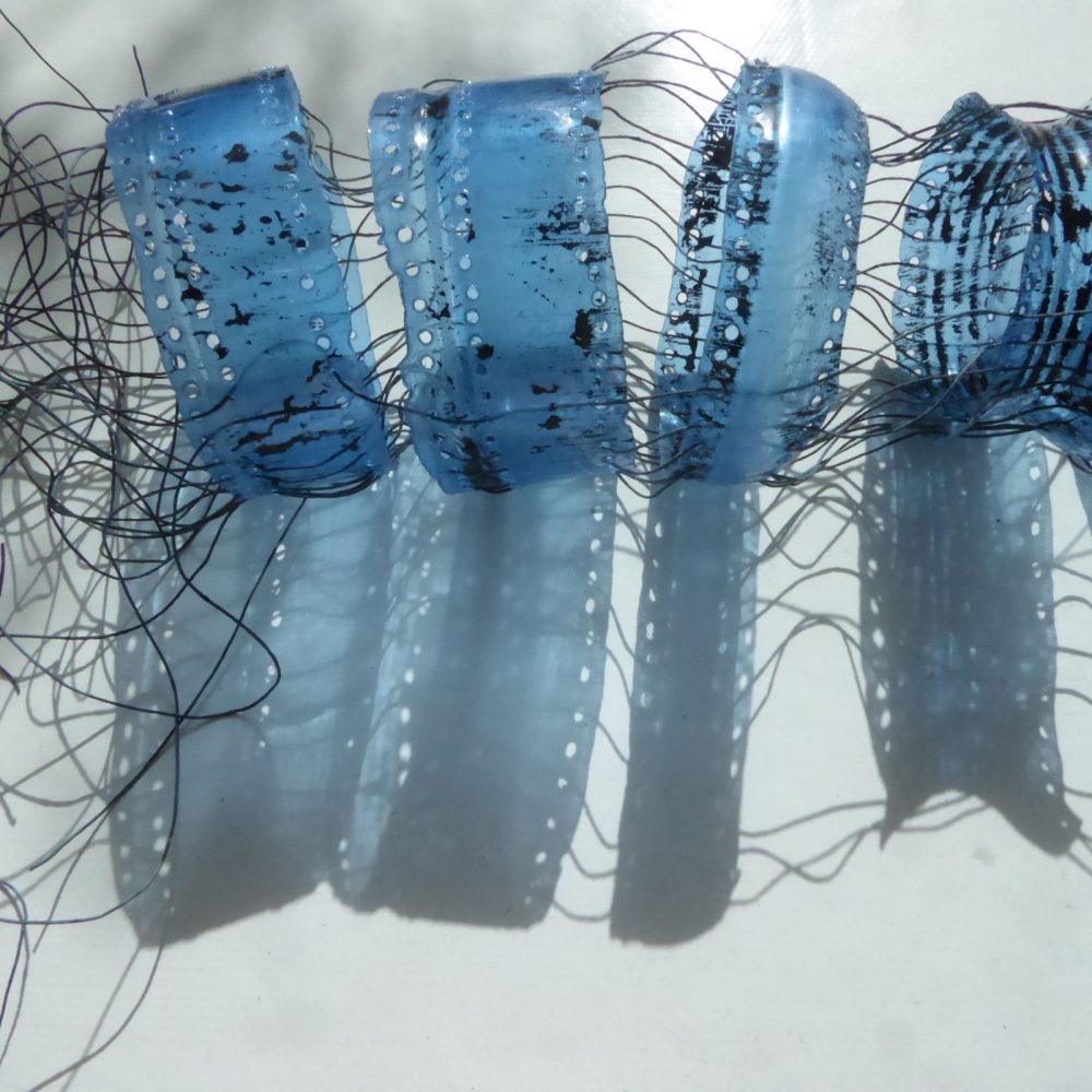 Fragments from blue plastic bottle laced together , creating a deep shadow of despair
