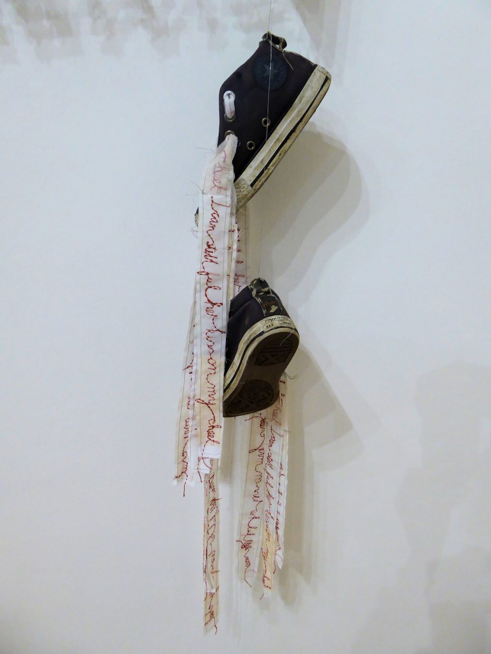 Pair of trainers with letter stitched laces hanging from end section