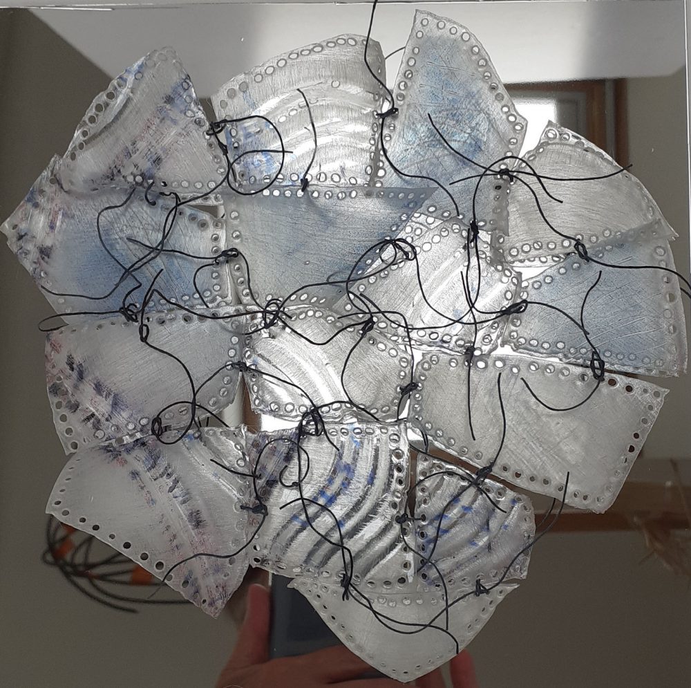 plastic bottle fragments laced together in front of mirror surface